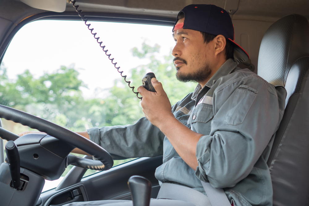 young Asian man smiling, confident, and proud his career. professional truck driver using radio communicate and talk. Smile and service with friendship of Truck driver, transportation and delivery