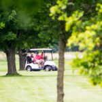 2018 FCC Annual Golf Tournament golfers in their cart through the trees