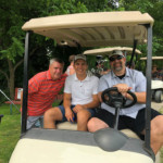 2018 FCC Annual Golf Tournament, golfers pose and smile in cart